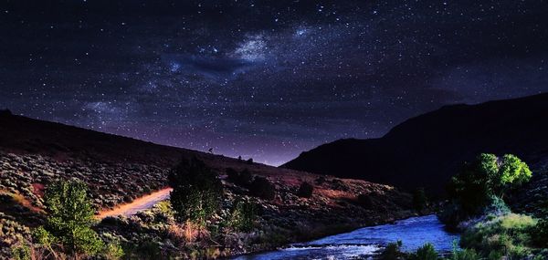 Scenic view of landscape against star field at night