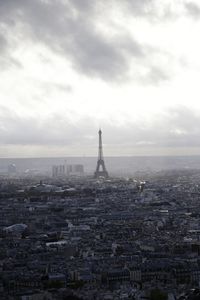 Aerial view of city buildings against cloudy sky tour eiffel