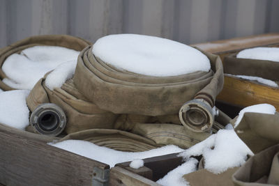 Coiled fire hoses laying in wooden boxes covered with snow