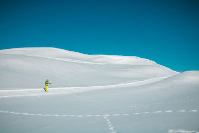 Person skiing on snowcapped mountain against blue sky