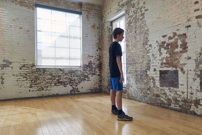 Side view of boy standing against wall