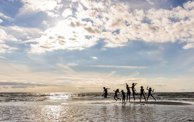 People enjoying on beach against sky