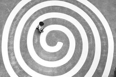 High angle view of man walking on spiral pattern markings on road