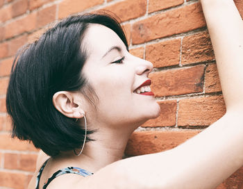 Close-up of smiling woman against wall