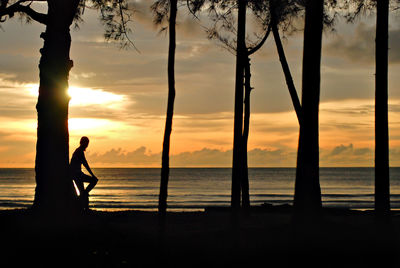 Silhouette man standing on beach against sky during sunset