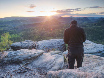 Tall adult photographer prepare camera for taking picture of fall mountains. photograph at daybreak