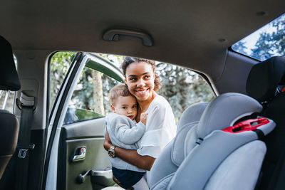 Mother with daughter standing by vehicle door