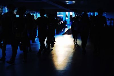 Silhouette people walking in illuminated corridor
