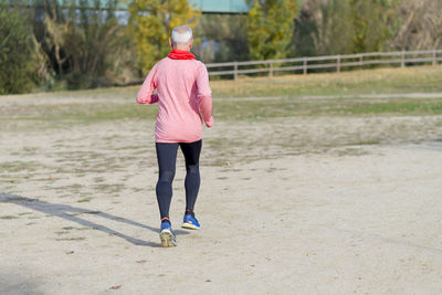 Rear view of man running on field