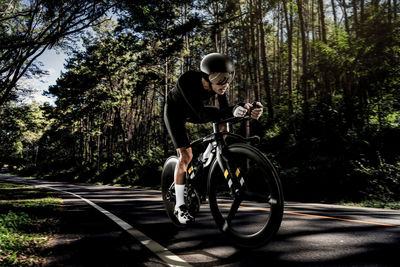 Man riding bicycle on road in forest