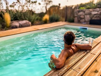 Rear view of woman sitting in swimming pool