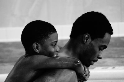 Side view of father piggybacking son at beach