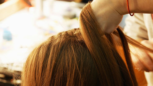 Cropped hands of female hairstylist styling girl hair