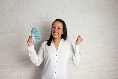 Portrait of a smiling young woman standing against wall