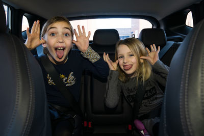 Portrait of children sitting in car making funny faces