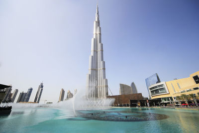 Fountain in city against clear sky