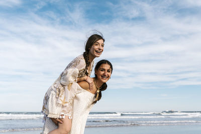 Woman smiling while standing on beach against sky