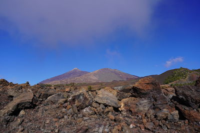 Scenic view of mountains against blue sky