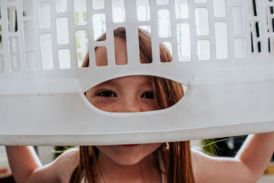 Goofy cute child peeking through laundry basket