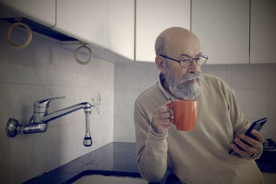 Portrait of young man drinking water while standing in bathroom