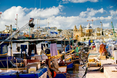 Boats moored at harbor in city against sky