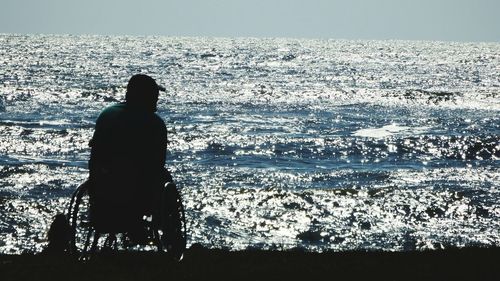 Rear view of silhouette woman standing at beach against clear sky