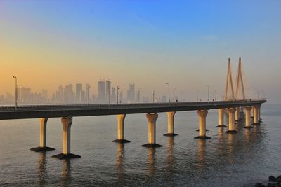 Bridge over sea against sky during sunset