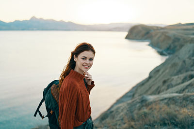 Portrait of smiling young woman standing at sea shore