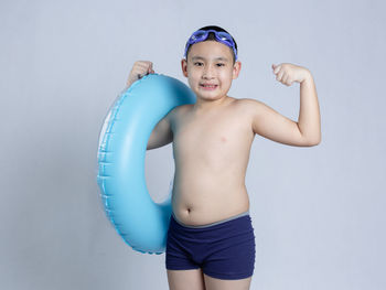 Portrait of shirtless boy standing against wall