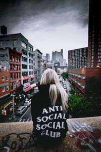 Rear view of woman standing by buildings in city