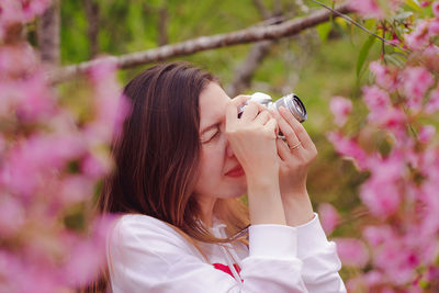 Close-up of woman photographing with camera while standing in park