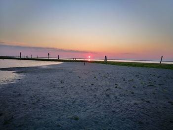 Scenic view of beach against clear sky during sunset