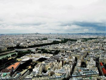 Aerial view of cityscape against cloudy sky