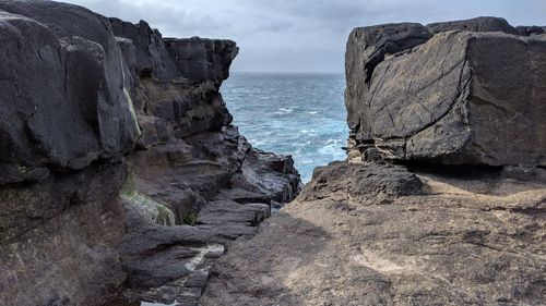 Rock formation on beach against sky