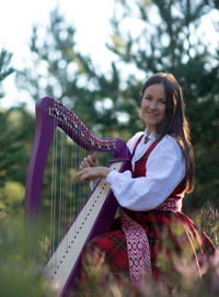 Portrait of smiling young woman playing harp