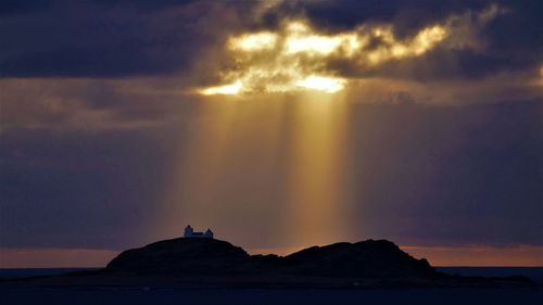 Scenic view of sea against dramatic sky during sunset