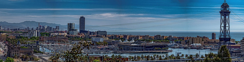 View of city at waterfront against cloudy sky