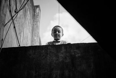 Low angle view of boy standing by retaining wall