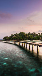 Pier over sea against sky during sunset