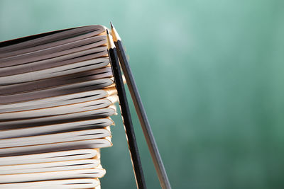 Stack of books with pencils at classroom against blackboard