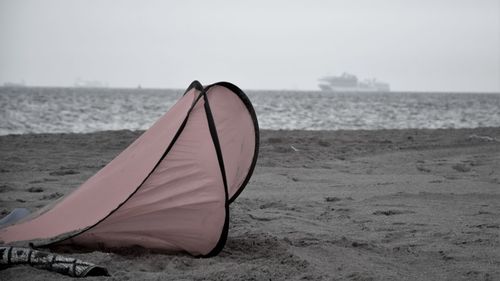 Deck chair on beach against sky