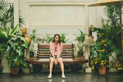 Portrait of woman sitting on potted plants