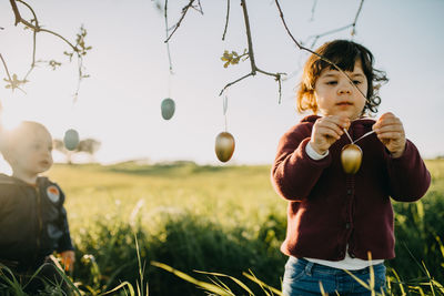 Full length of girl hanging easter eggs on tree