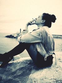 Side view of young man sitting on beach