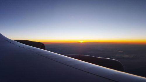 Airplane wing against sky during sunset