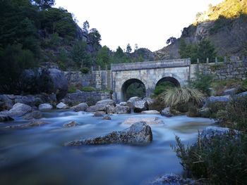 Arch bridge over river against sky