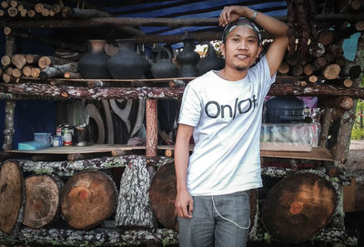 Portrait of man standing against firewood