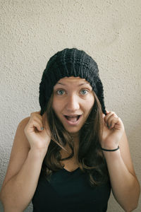 Young woman wearing knit hat against wall at home