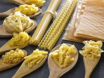 Various pasta in wooden spoons on slate