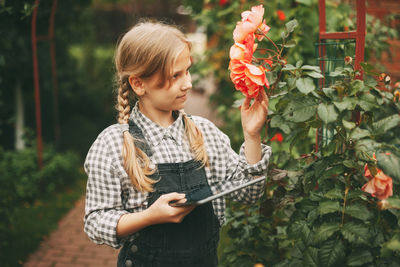 Close-up of woman holding flower while standing by plants